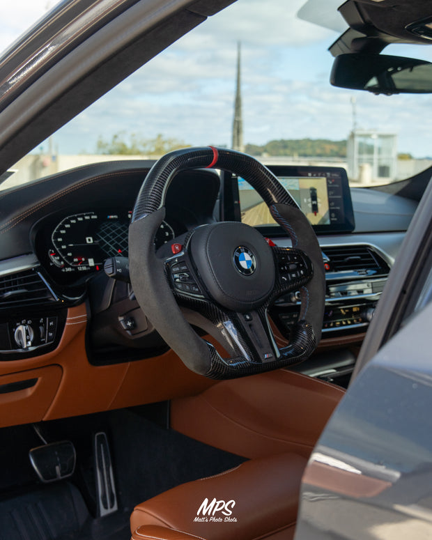 Close-up of a BMW car interior with a custom steering wheel and dashboard