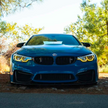 Blue BMW f80 m4 parked on a road with trees in the background